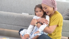   Person sitting on the floor holding another person in their hands while wearing a head scarf