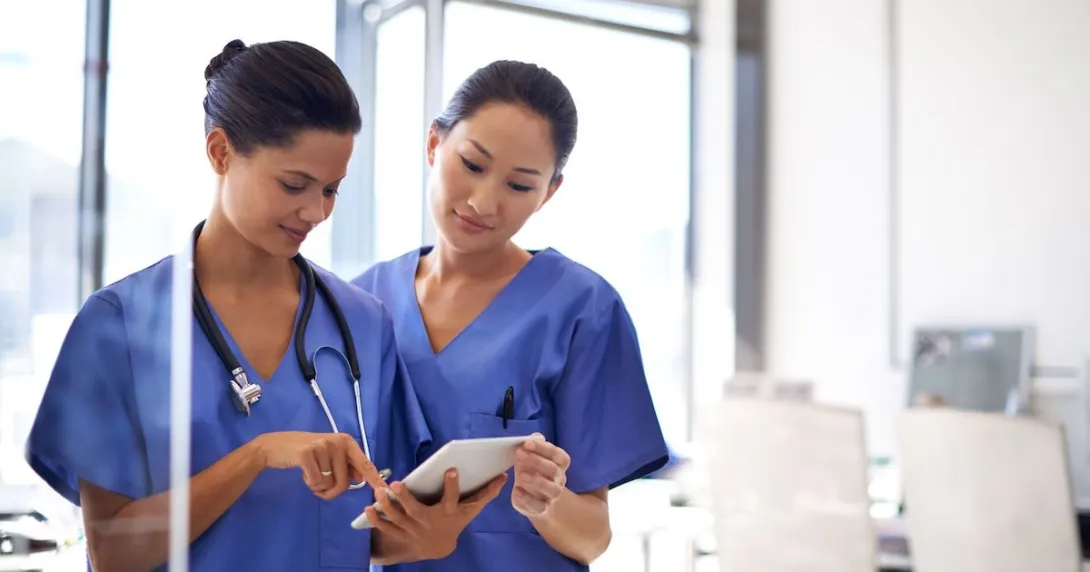 Two healthcare providers looking at a tablet Two healthcare providers looking at a tablet